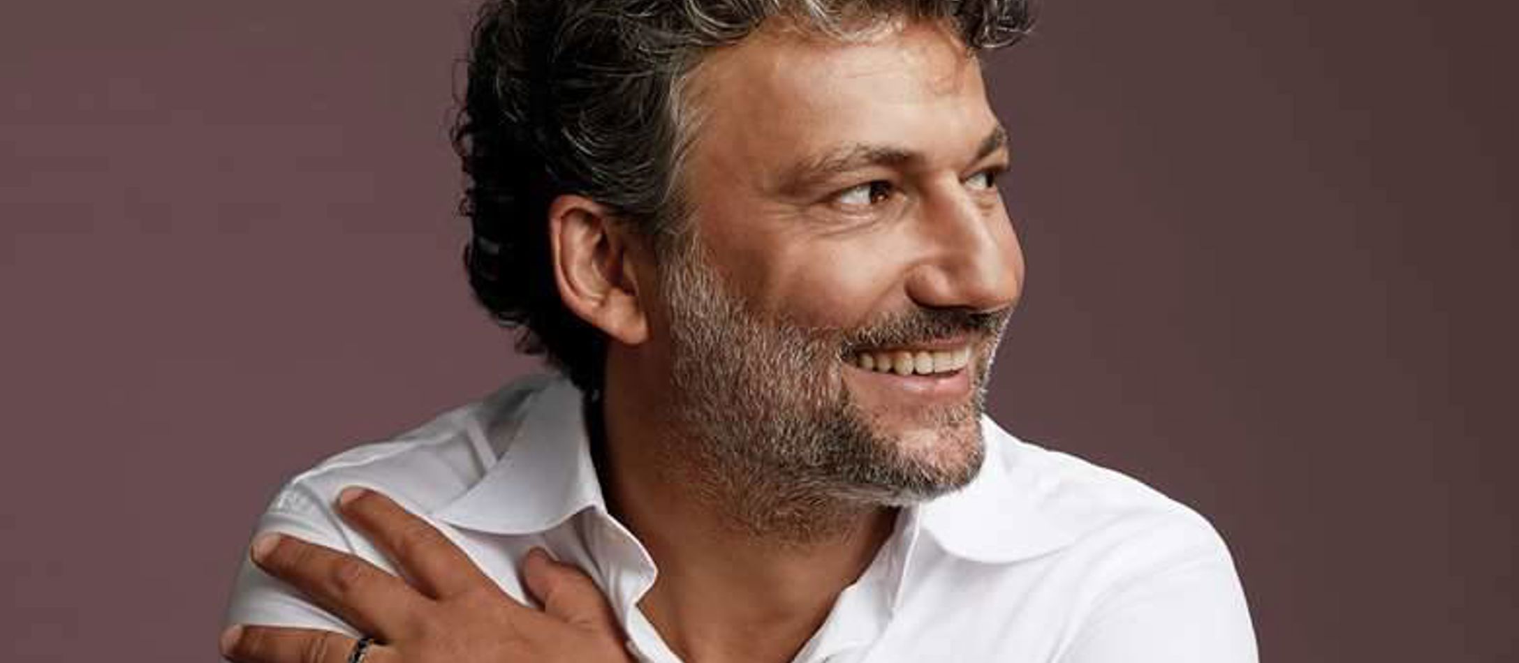 Jonas Kaufmann iført hvid skjorte foran boudeaux væg