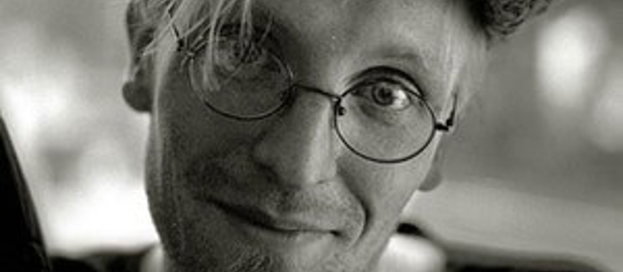 Lauri Supponen med briller og bowlerhaft i sort/hvid foran sløret baggrund.