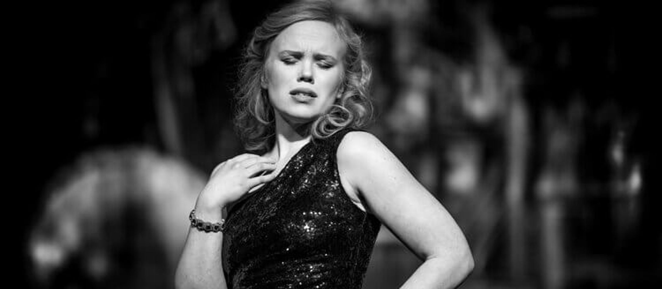 Beate Mordal i sort/hvid iført elegant sortglimmeret kjole, lukkede øjne og krøllet smukt hår.