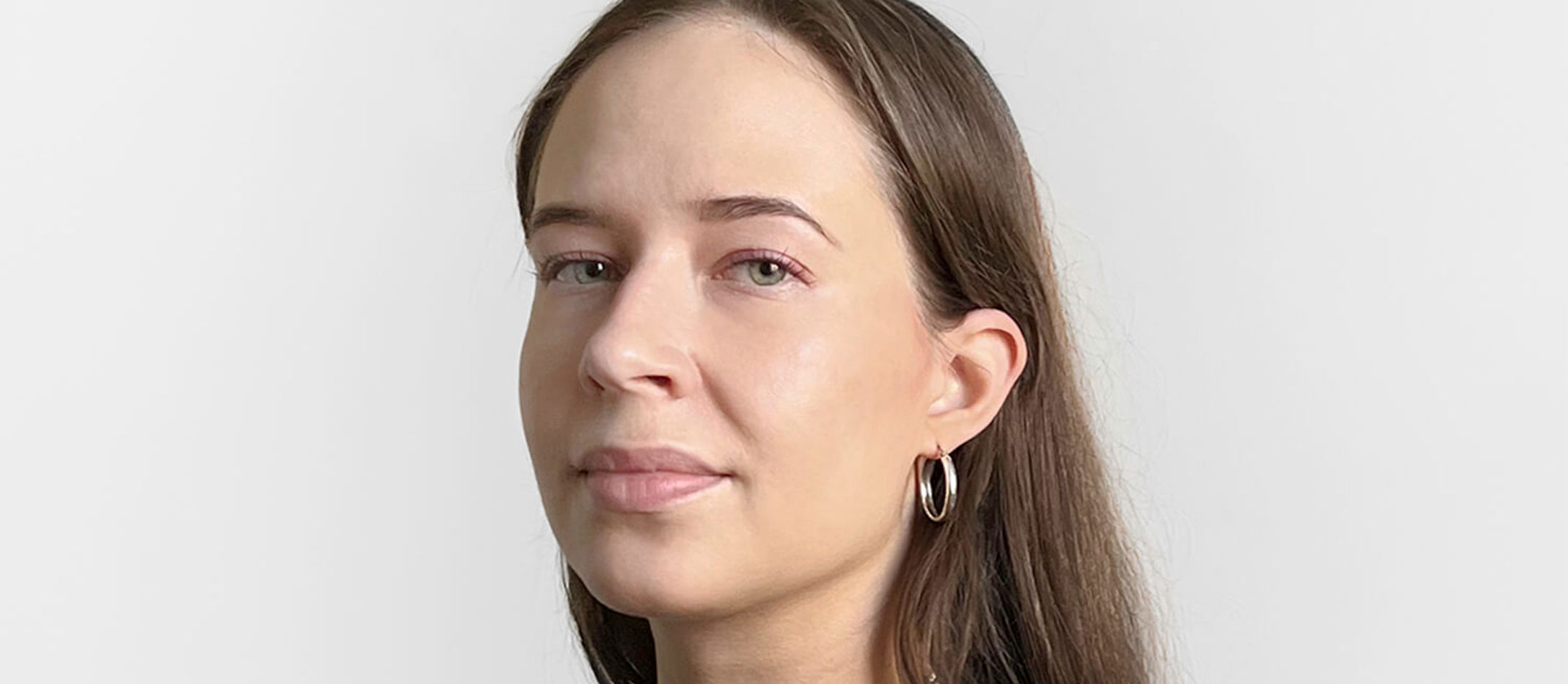 Irene Suosalo med glat brunt hår og lys fin hud iført sort langarmet bluse og halvlang sølvhalskæde og runde små øreringe